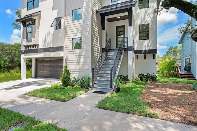 view of exterior entry featuring driveway, an attached garage, and stucco siding