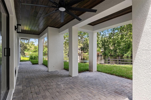 view of patio / terrace with a water view, ceiling fan, and fence