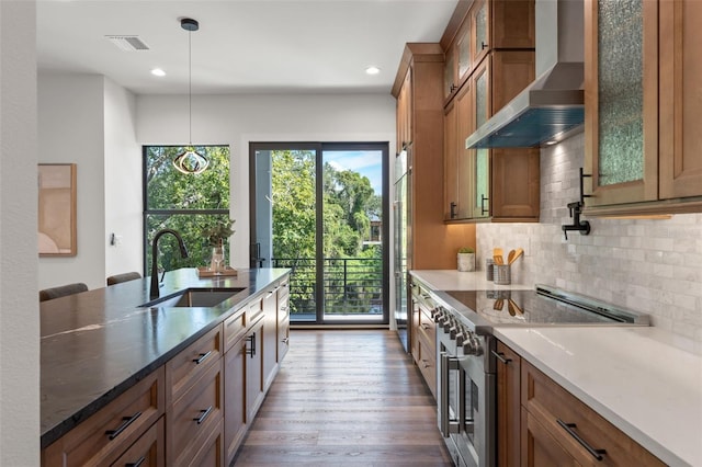 kitchen with pendant lighting, decorative backsplash, sink, stainless steel appliances, and wall chimney exhaust hood