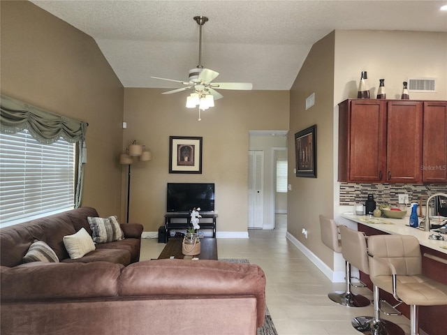 living room with ceiling fan, a textured ceiling, and vaulted ceiling