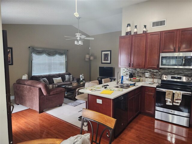 kitchen featuring vaulted ceiling, light hardwood / wood-style flooring, appliances with stainless steel finishes, sink, and ceiling fan