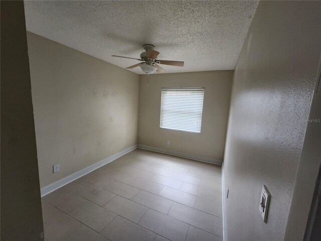 empty room featuring a textured ceiling, light tile patterned floors, and ceiling fan