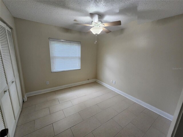 unfurnished bedroom with a textured ceiling, light tile patterned floors, and ceiling fan