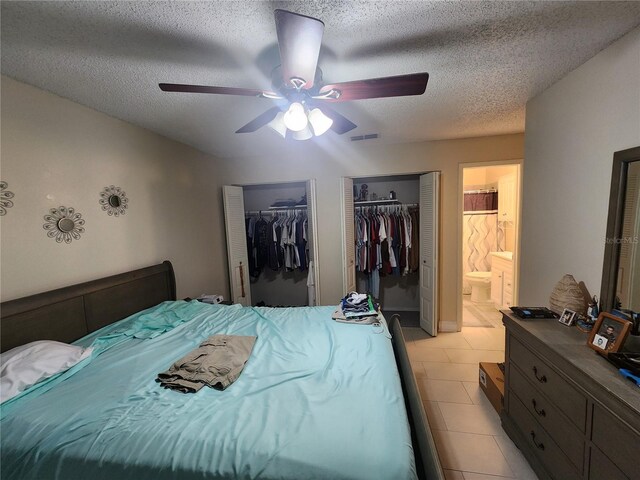 bedroom with a textured ceiling, light tile patterned floors, ceiling fan, and ensuite bathroom