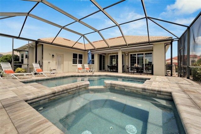 view of swimming pool featuring glass enclosure, an in ground hot tub, and a patio