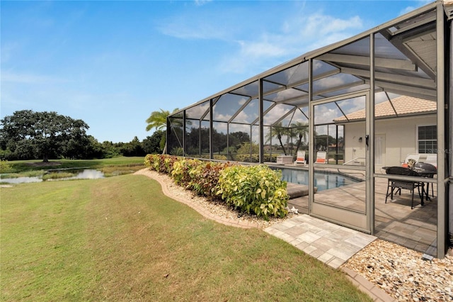 view of yard with a patio, a water view, and glass enclosure