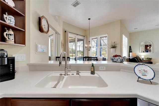 kitchen featuring a chandelier, pendant lighting, a textured ceiling, and sink