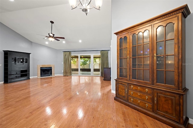 unfurnished living room featuring light wood-style flooring, a fireplace, high vaulted ceiling, and ceiling fan with notable chandelier