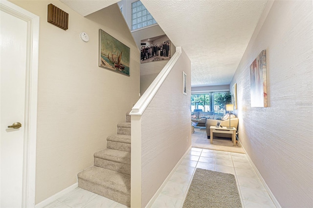 stairway featuring tile patterned floors and a textured ceiling