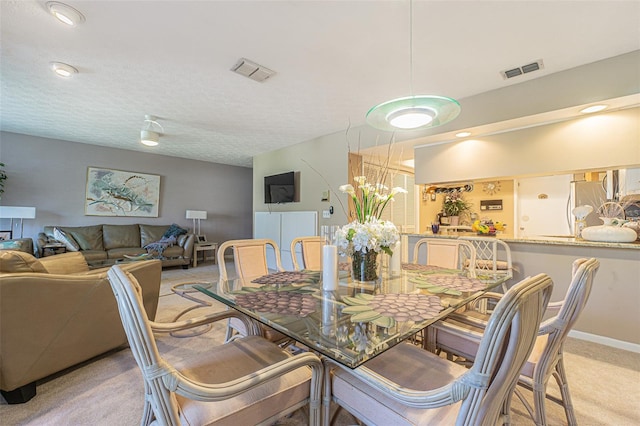 carpeted dining room with a textured ceiling