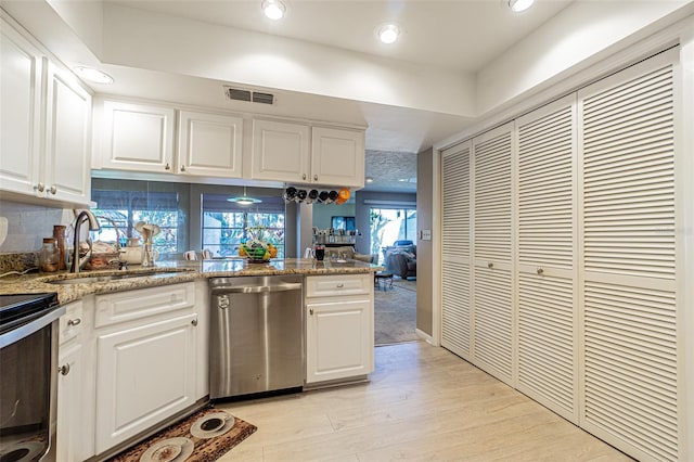 kitchen with appliances with stainless steel finishes, white cabinets, sink, and light wood-type flooring