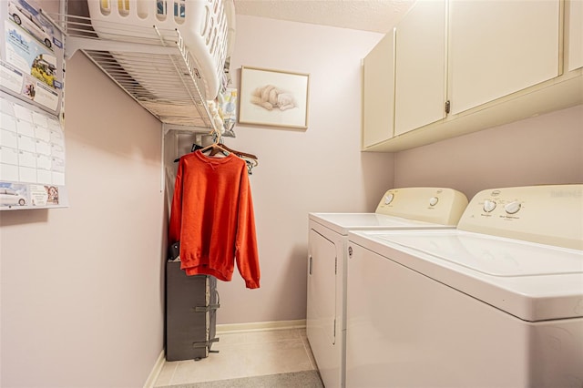 clothes washing area featuring cabinets, washer and dryer, and light tile patterned flooring