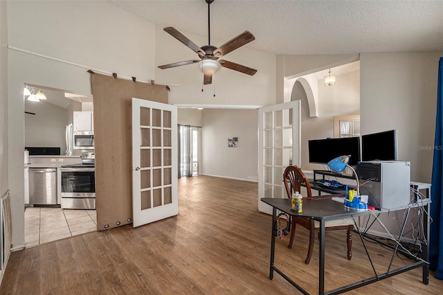 office with a textured ceiling, high vaulted ceiling, and light hardwood / wood-style flooring