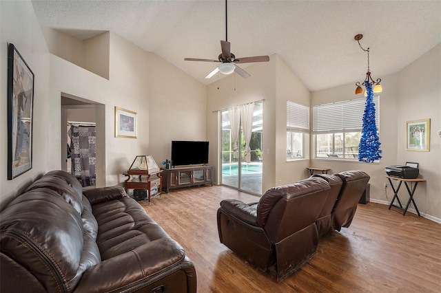 living room featuring high vaulted ceiling, ceiling fan, a textured ceiling, and light hardwood / wood-style flooring