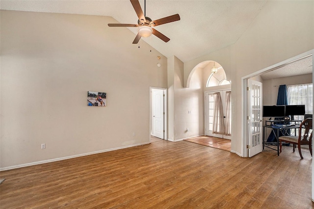 unfurnished living room featuring a textured ceiling, hardwood / wood-style flooring, high vaulted ceiling, and ceiling fan