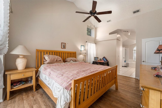 bedroom featuring high vaulted ceiling, wood-type flooring, connected bathroom, and ceiling fan