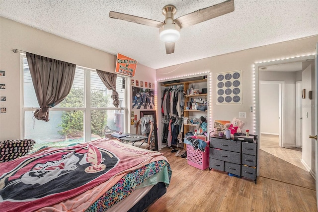 bedroom with a textured ceiling, ceiling fan, a closet, and light hardwood / wood-style floors