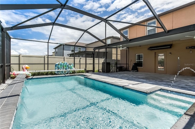 view of pool featuring pool water feature, glass enclosure, a patio, and ceiling fan