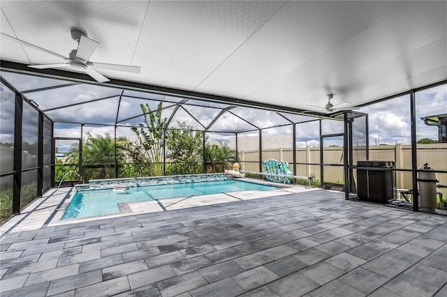 view of pool with glass enclosure, pool water feature, ceiling fan, and a patio