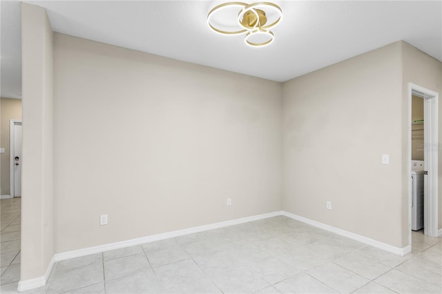 empty room with light tile patterned floors and washer / dryer