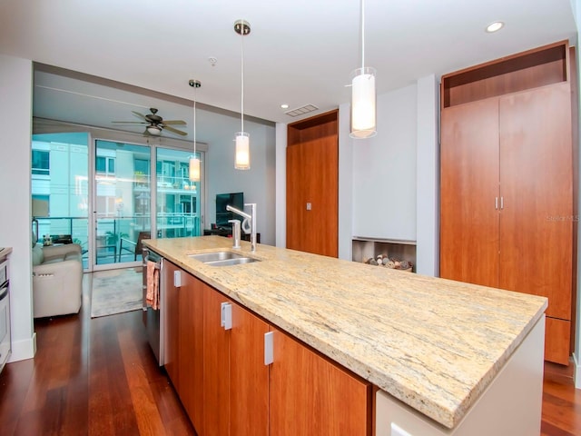 kitchen featuring pendant lighting, light stone countertops, sink, and a center island with sink