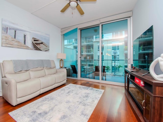 living room featuring hardwood / wood-style flooring, ceiling fan, and a wall of windows