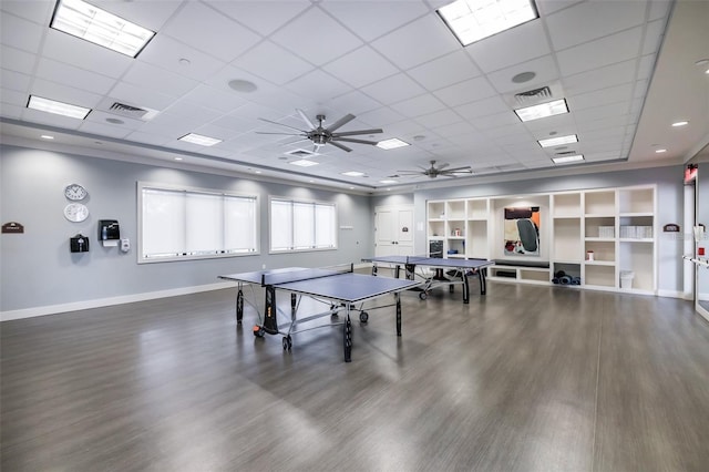 rec room with a paneled ceiling, ceiling fan, and dark wood-type flooring