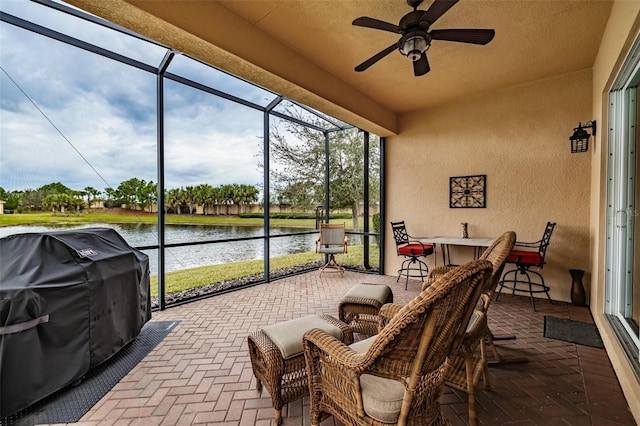 sunroom featuring ceiling fan and a water view