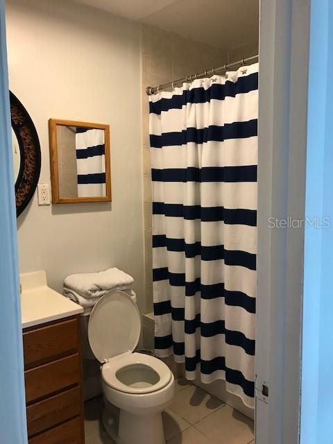 bathroom featuring walk in shower, vanity, toilet, and tile patterned floors