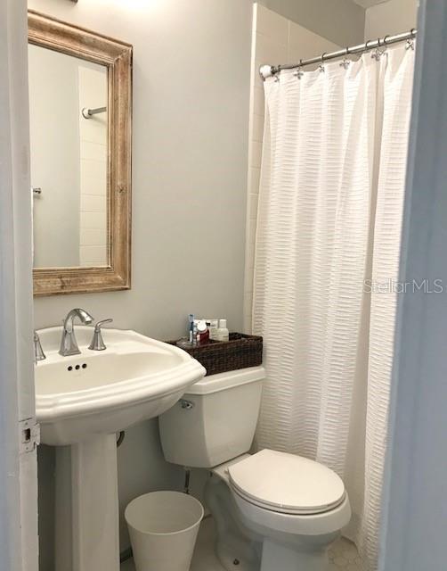 bathroom with a shower with curtain, sink, and toilet