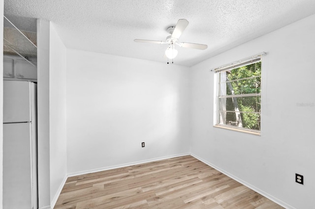 interior space featuring a textured ceiling, light hardwood / wood-style flooring, ceiling fan, and white fridge