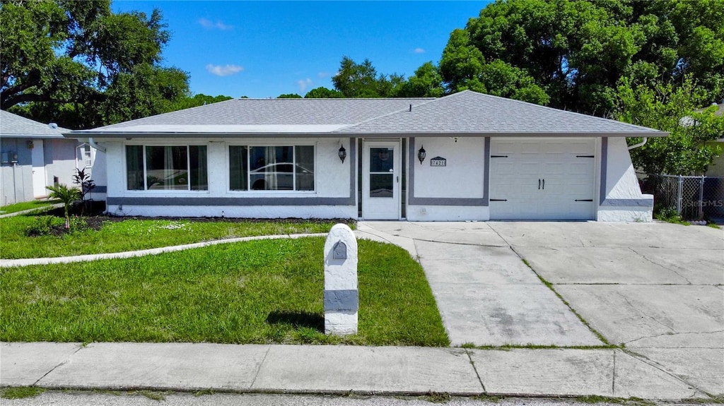 ranch-style home featuring a garage, concrete driveway, a front lawn, and stucco siding