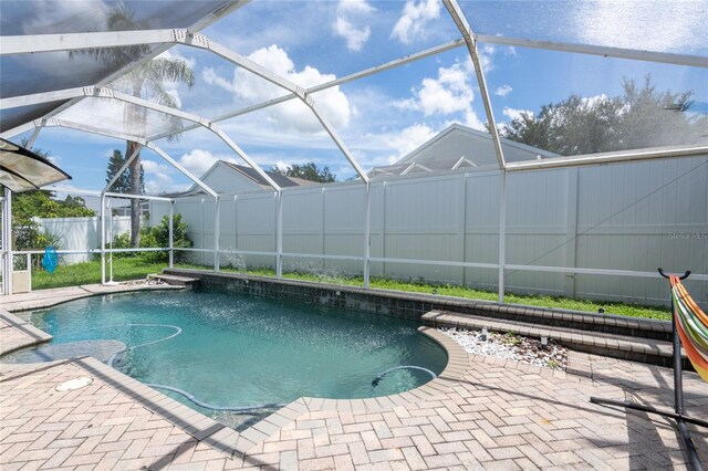 view of pool featuring glass enclosure and a patio