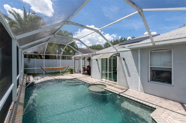 view of swimming pool featuring pool water feature, a patio, and glass enclosure