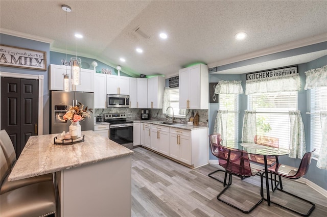 kitchen with stainless steel appliances, a center island, sink, vaulted ceiling, and light hardwood / wood-style floors