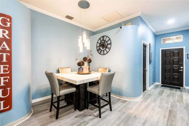 dining area featuring crown molding and light hardwood / wood-style flooring