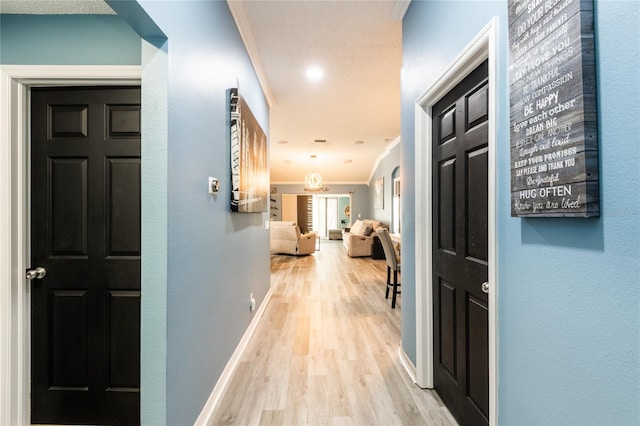 corridor featuring light wood-type flooring and ornamental molding