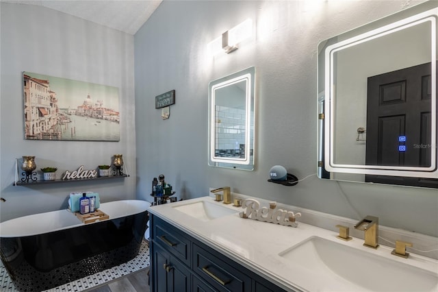 bathroom featuring a textured ceiling, vanity, and a washtub