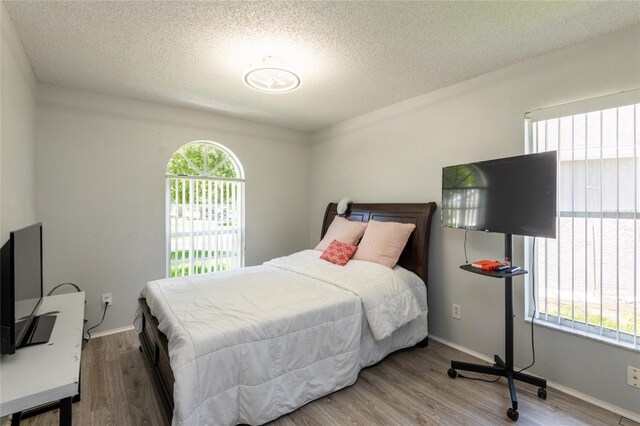 bedroom featuring multiple windows, wood-type flooring, and a textured ceiling