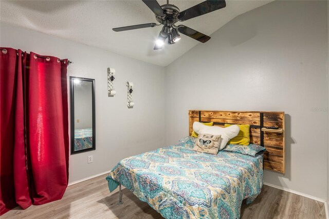 bedroom featuring lofted ceiling, wood-type flooring, a textured ceiling, and ceiling fan