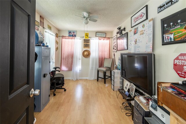 home office featuring a textured ceiling, light hardwood / wood-style flooring, and ceiling fan