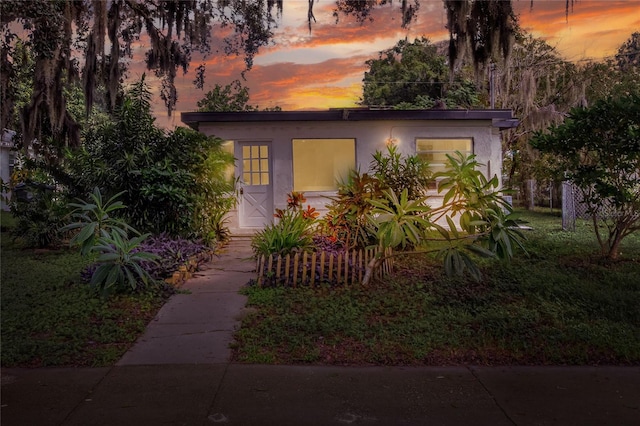 view of front of home featuring stucco siding and a lawn