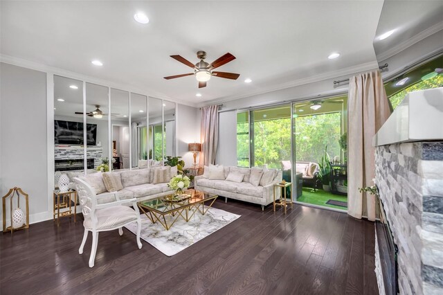 living room with crown molding, ceiling fan, a stone fireplace, and dark hardwood / wood-style flooring