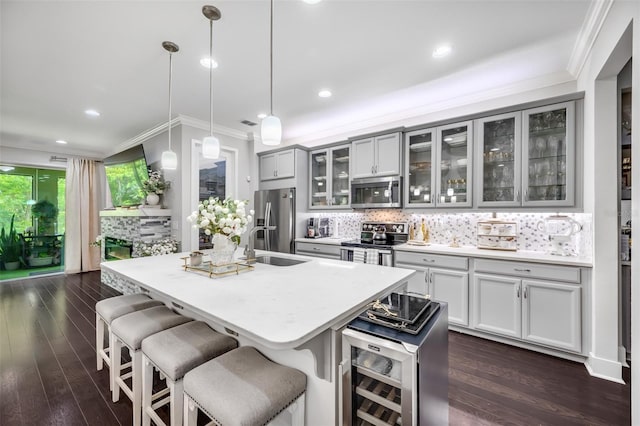 kitchen featuring hanging light fixtures, stainless steel appliances, dark hardwood / wood-style flooring, a center island with sink, and a breakfast bar