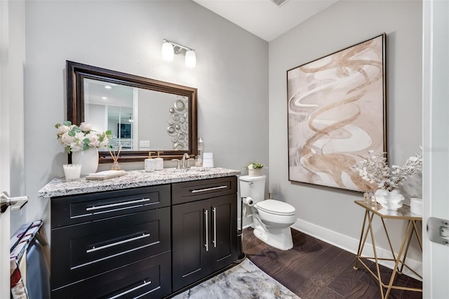 bathroom with vanity, toilet, and hardwood / wood-style flooring