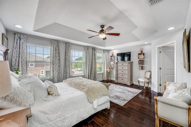 bedroom featuring a tray ceiling, dark hardwood / wood-style flooring, and ceiling fan