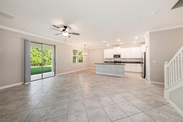 kitchen featuring crown molding, appliances with stainless steel finishes, white cabinetry, an island with sink, and ceiling fan