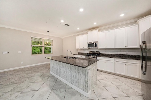 kitchen with a center island with sink, stainless steel appliances, sink, white cabinetry, and dark stone countertops