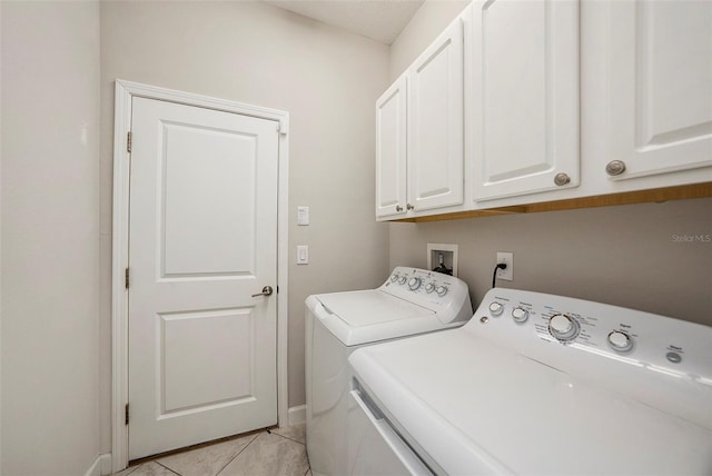 clothes washing area featuring light tile patterned floors, washing machine and clothes dryer, and cabinets