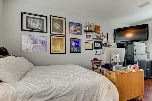 bedroom featuring stainless steel fridge and dark hardwood / wood-style floors